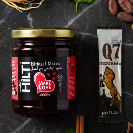 Jar of Hilt Bitkisel Macun with a tube of Q7 chocolate on a dark surface.